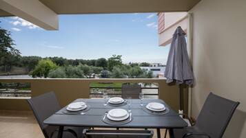 Ein Balkon mit Tisch für zwei Personen, mit Blick auf eine malerische Landschaft aus Bäumen und Gebäuden.