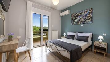 Ein Schlafzimmer mit Bett, Schreibtisch, Stuhl, Nachttisch und Blick ins Freie.