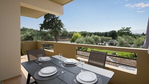 Un balcon avec une table dressée pour le dßner, donnant sur un jardin et sur des bùtiments situés au loin.