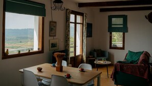 Una stanza accogliente con un tavolo da pranzo in legno, sedie, un divano e vista sulla campagna.