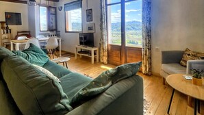 Un accogliente soggiorno con divano, televisione e zona pranzo con tavolo e sedie.
