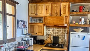 Cucina con pensili e basi in legno, lavello, piano cottura e frigorifero.