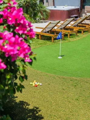 Un campo de golf con un mástil de bandera, sillas de descanso y un jacuzzi.