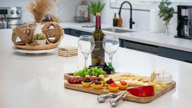 Cozinha com iluminação pendente, uma garrafa de vinho e um prato de frutas.