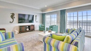 Een woonkamer met gestreepte banken, een flatscreen-televisie en een balkon met uitzicht.
