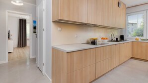 A modern kitchen with wooden cabinets, a white countertop, and a window providing natural light. - Spacious Apartment | 2 Balconies | Close to the Beach (Gdańsk)