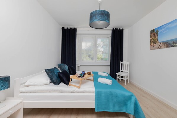 A neatly arranged bedroom with a bed, bedside table, and a window with curtains.