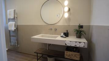 Une salle de bain moderne avec un grand lavabo, un miroir rond et un porte-serviettes.