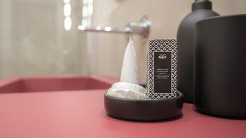 Un tocador de baño con un dispensador de jabón negro, una botella negra y una caja de pañuelos.