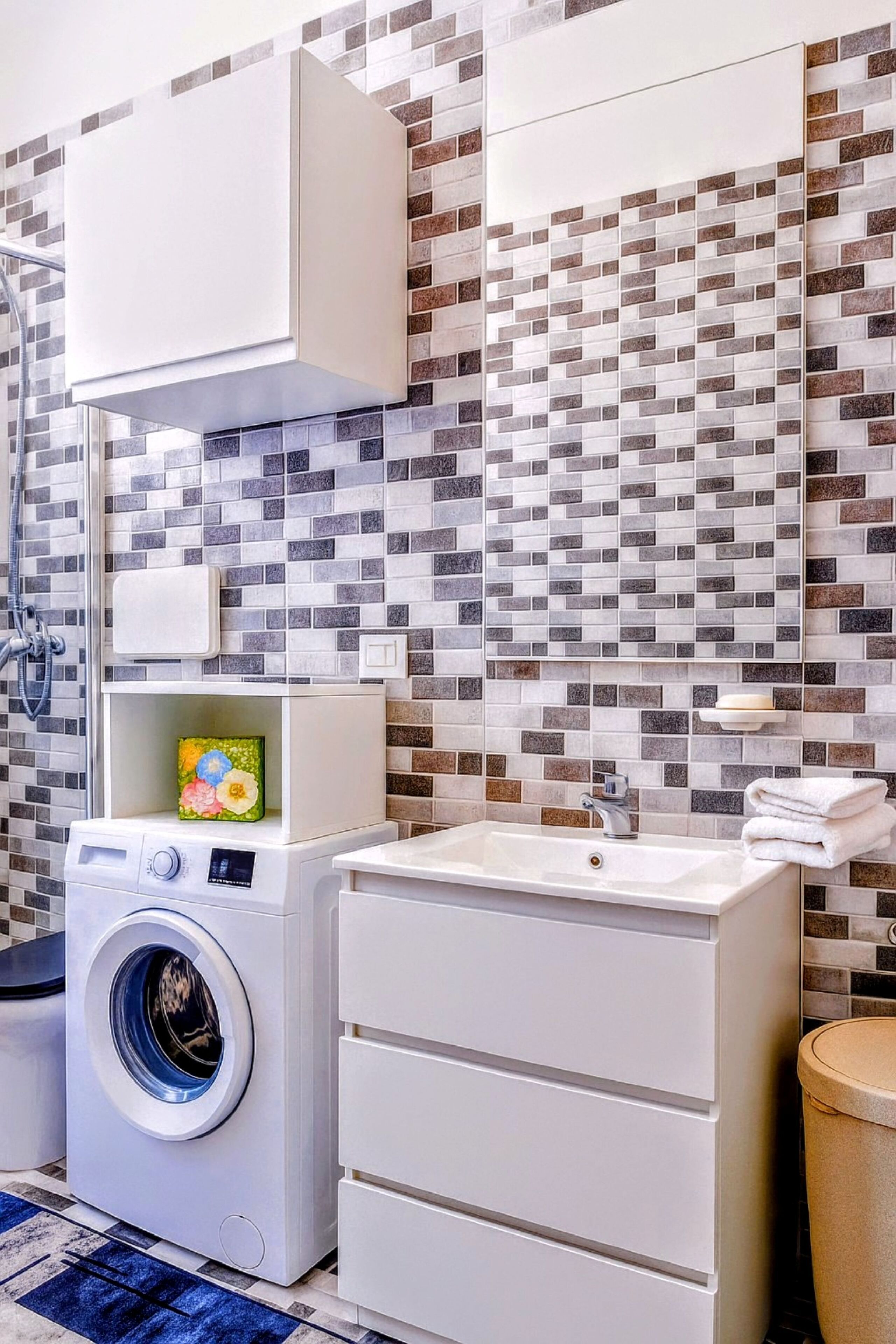 A laundry area with a washing machine, a sink, and a mirror.