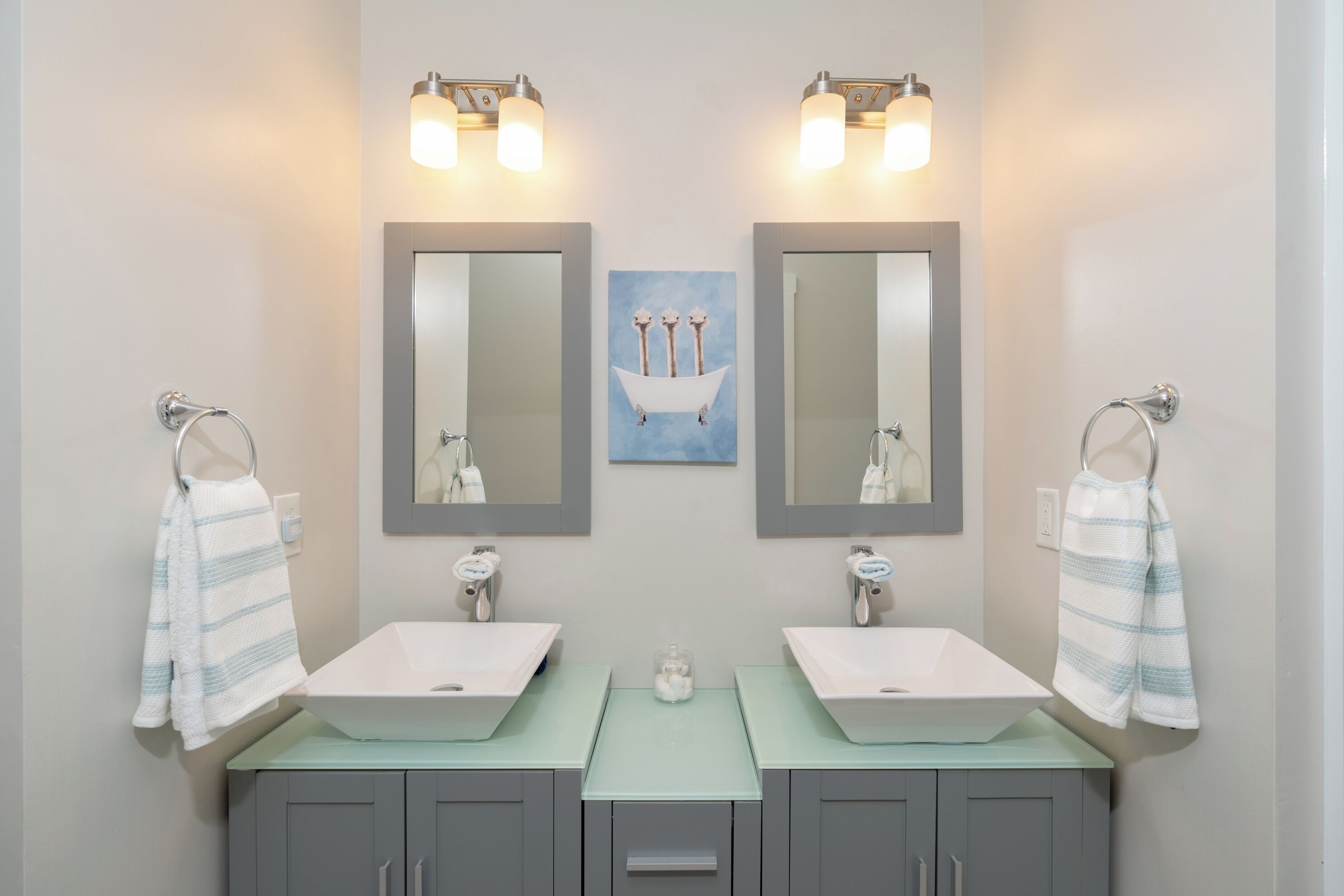 Un bagno con due lavandini, uno specchio e un porta asciugamani.