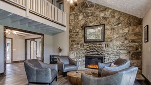 Un salón amplio con chimenea de piedra, sofás de cuero y una mesa de centro de madera.