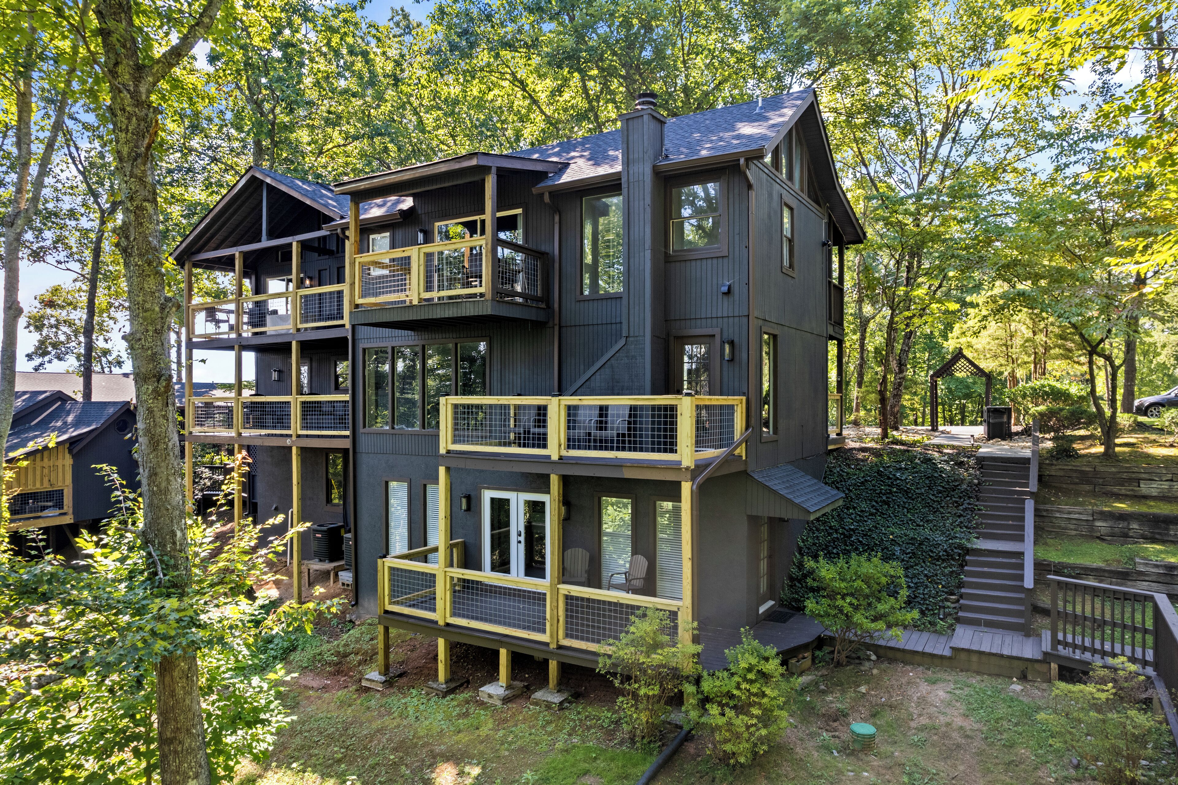 A multi-story house with balconies and a deck, surrounded by trees.