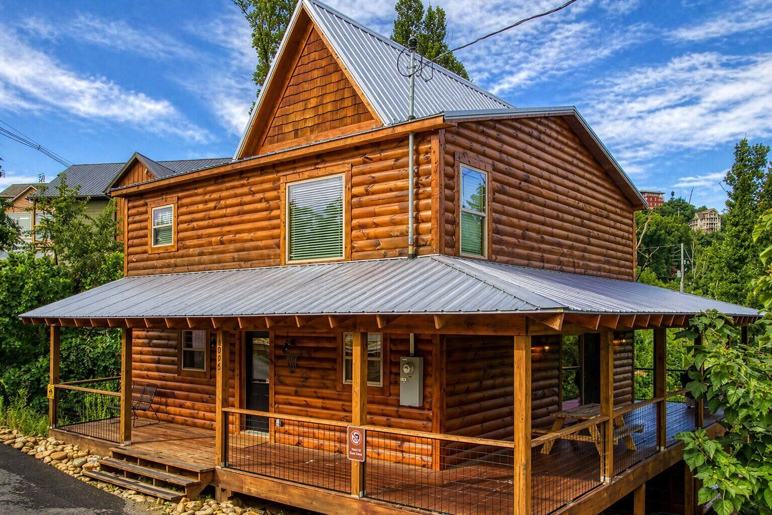 A log cabin with a porch, a metal roof, and a visible electrical box.