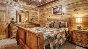 A wooden cabin bedroom with a bed, dresser, nightstand, and a ceiling fan. - Old Glory - WIFI, Hot Tub, Game Room, Free Attraction Tickets!!! (Sevierville)