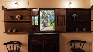 Habitació amb un armari de fusta, dues cadires i una estant amb objectes decoratius.