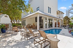 A modern house with a pool, outdoor seating, and a covered patio area.