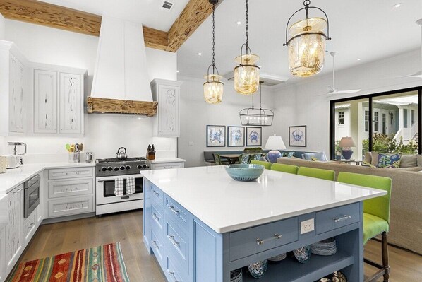 A modern kitchen with white cabinetry, a central island, and a dining area with a sofa and table.