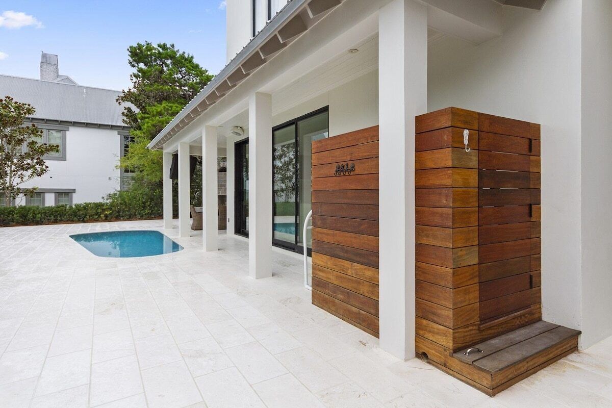 Une maison moderne dotée d’une piscine, d’un espace extérieur couvert et d’un mur en bois.