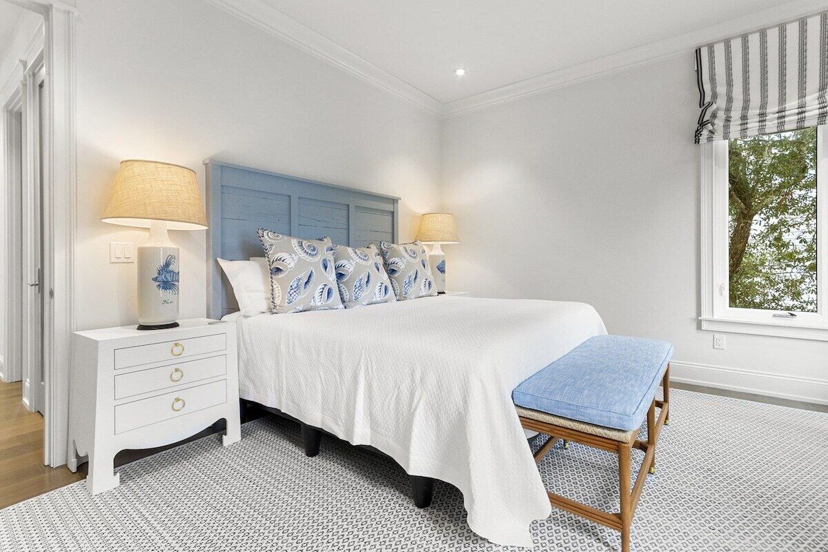 A bedroom with a bed, bedside tables, a bench, and a window.