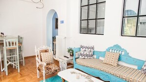 Um quarto com um sofá azul, uma mesa branca e uma poltrona com estampa de leopardo.