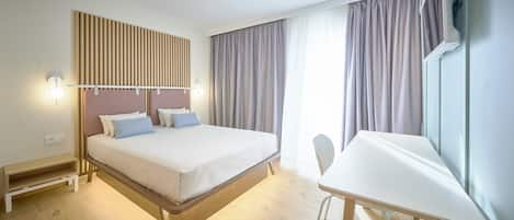 Et moderne hotelværelse med seng, sengebord og skrivebord med stol.