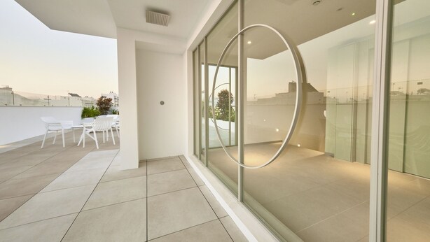 A modern interior with a glass wall, a white ceiling, and a tiled floor. - Hotel Leonor (Conil de la Frontera)