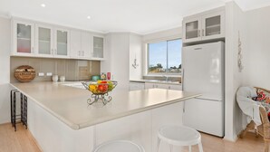 A modern kitchen with white cabinets, a large island, and a view of the outside.