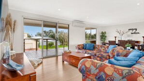 A modern living room with a large sofa, a coffee table, and a dining area.