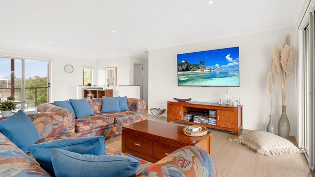A modern living room with a sofa set, a coffee table, and a TV mounted on the wall.