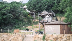 Una estructura al aire libre de varios niveles con escalones de piedra y una valla de madera, rodeada de abundante vegetación.