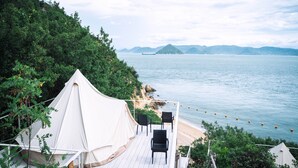 Un área con toldos, una terraza, sillas y vistas al mar y a islas distantes.