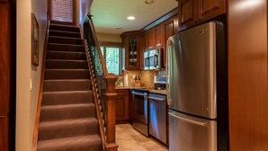Une cuisine avec un escalier en bois, des appareils électroménagers en acier inoxydable et des armoires en bois.