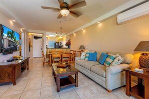 A living room with a sofa, coffee table, and dining area with chairs.