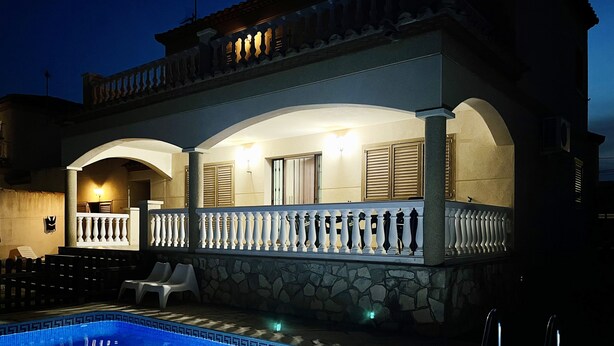 Un bâtiment à deux étages doté d’une piscine, de murs en pierre et d’un balcon orné de balustrades blanches.