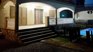 Une maison à deux étages avec une piscine, des marches en pierre et un balcon doté de balustrades.