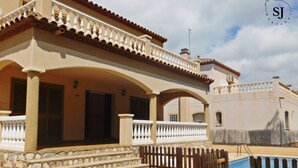 Une maison à deux étages dotée d’un balcon, d’une piscine et d’un escalier en pierre menant à l’entrée.