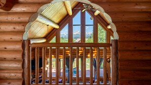 A wooden log cabin with a large arched window overlooking a mountain landscape. - Beautiful Moran Home with spectacular Teton Views (Moran)