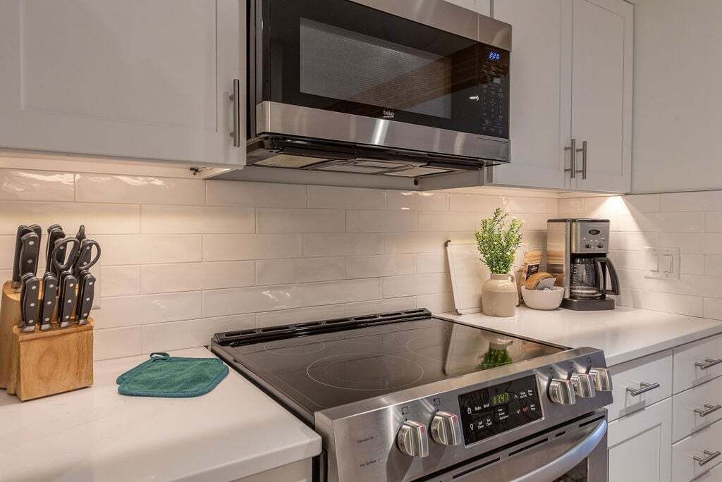 A modern kitchen with stainless steel appliances, including a microwave, stove, and coffee maker.