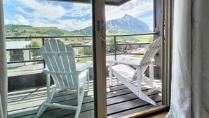 A balcony with a white chair and table, a mountain view, and a clear sky. - Modern Mountain Townhome with Mountain Views! (Mount Crested Butte)