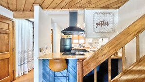 A kitchen with a wooden ceiling, a black stove, and a 'gather' sign on the wall. - Modern Mountain Townhome with Mountain Views! (Mount Crested Butte)