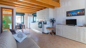 Een moderne keuken met houten balken, een eethoek en een woonkamer met een bank.
