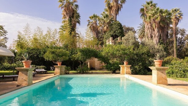 A swimming pool with a clear blue water surface, surrounded by lush greenery and tall palm trees. - Apartment 'Tenuta Donna Vittoria Edera' with Mountain View, Wi-Fi and Air Conditioning (Trapani)