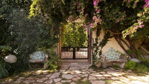 A stone pathway leading to a gate, surrounded by lush greenery and decorative tiles. - Apartment 'Tenuta Donna Vittoria Edera' with Mountain View, Wi-Fi and Air Conditioning (Trapani)