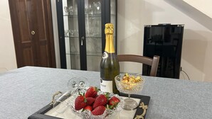 Una mesa con una botella de champán, un cuenco de fresas y una copa.