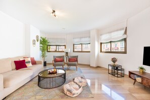 A spacious living room with a sofa, chairs, a coffee table, and a TV.