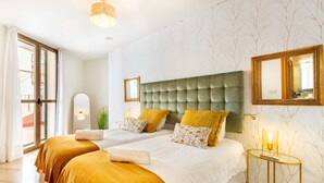 Une chambre d’hôtel avec deux lits, un grand miroir, une table de chevet avec une lampe et une vue à travers une porte vitrée.