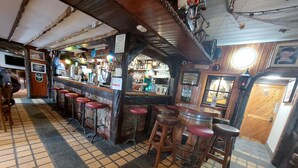Uma área de bar com bancos, um barril de madeira e uma placa indicando um centro de cuidados para casais.