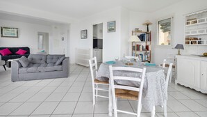 A modern living room with a grey sofa, a dining table with white chairs, and a bookshelf. - Seafront, beautiful apartment for 4 with terrace (La Baule-Escoublac)