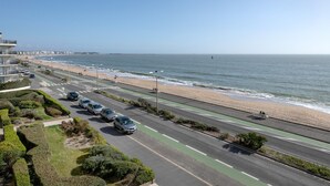 A coastal road with a beach on one side, cars parked along the road, and a clear view of the ocean. - Seafront, beautiful apartment for 4 with terrace (La Baule-Escoublac)